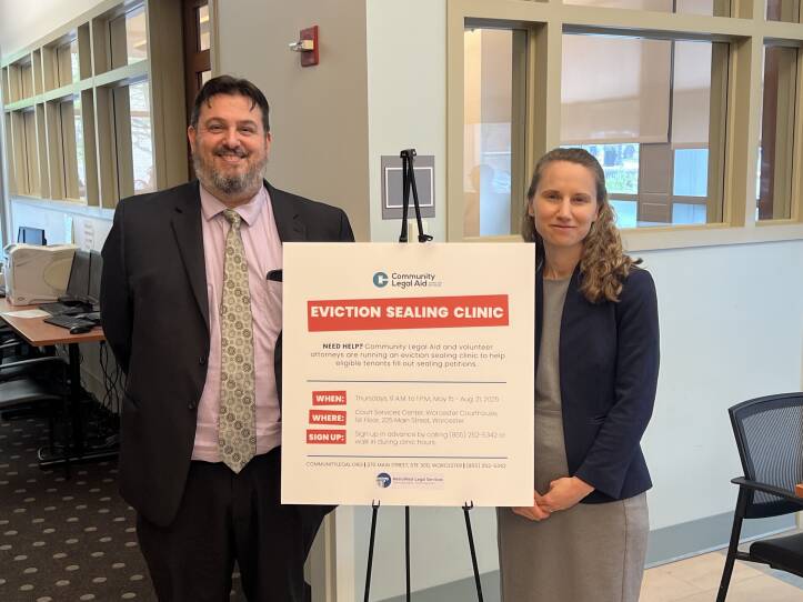 Photo of two attorneys standing beside sign advertising an Eviction sealing Clinic at the Worcester Courthouse
